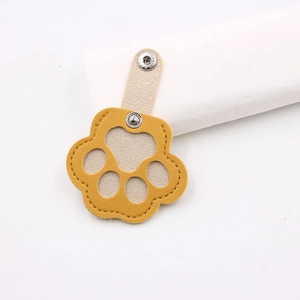 Detail of yellow cat paw shaped leather keychain with a silver metal snap button closure
