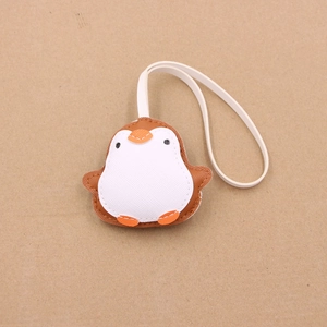 Detail of penguin leather charm with fine stitching and white lanyard on brown base