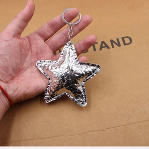 Macro shot of silver star keychain with embossed crocodile leather texture and metal ring