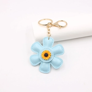 Detail view of light blue leather flower keychain with golden hardware and sunflower core