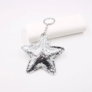 Macro detail of silver star keychain with metallic wrinkled leather texture and stitching