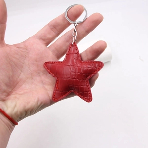 Detail of red crocodile pattern leather star keychain with silver metal ring and fine stitching
