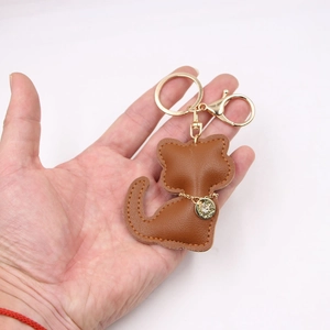 Brown leather kitten keychain with golden hardware and rhinestone charm on white background