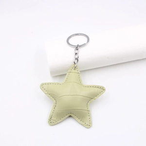 Close-up of mint green crocodile embossed star keychain with silver metal ring