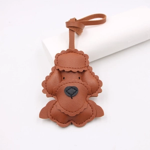 Brown leather poodle bag charm with scalloped edges and stitching on white pedestal