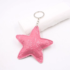 Detailed close-up of pink star keychain with snake pattern leather and silver hardware