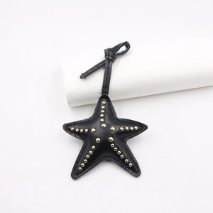 Détail d'un pendentif étoile en cuir noir avec rivets dorés et coutures fines
