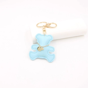 Close-up of blue leather bear keychain with hand-stitched edges and golden hardware