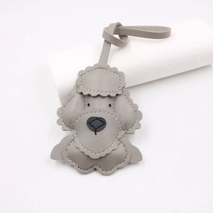 Detail view of a grey multi-layer leather teddy dog charm with white stitching and leather strap