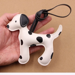 Bijou de sac en cuir motif dalmatien avec cordon noir, présenté à la main