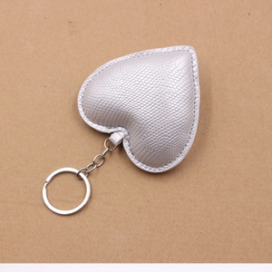 Gros plan d'un porte-clés cœur en cuir argenté avec texture peau de serpent gaufrée