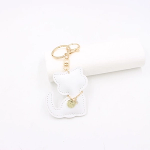 Detail of white leather cat keychain with gold chain collar and engraved pendant