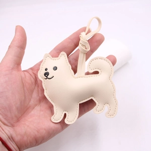 Detail of a handmade cream puppy leather bag charm held in hand with visible stitching