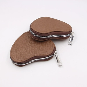 Minimalist brown heart-shaped leather coin purse with silver zipper on white background