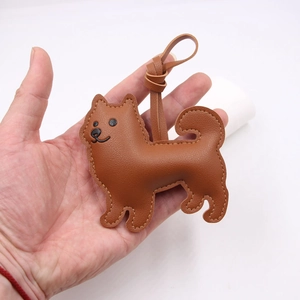 Close-up of a brown leather dog bag charm with white stitching and embroidered details
