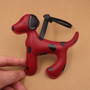 Détail d'un charm chien dalmatien en cuir rouge avec pois noirs et coutures soignées