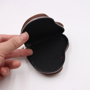 Internal view of a heart-shaped brown leather coin purse showing black fabric lining and zipper
