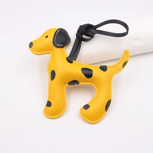 Détail d'un charme de chien en cuir jaune à pois avec sangle noire et couture soignée