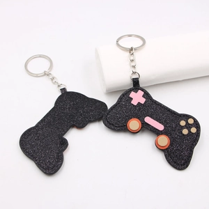 Macro view of black glitter game controller keychain with pink buttons and silver chain