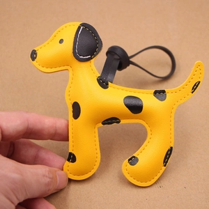 Détail du bijou de sac en cuir chien tacheté jaune tenu par une main réelle