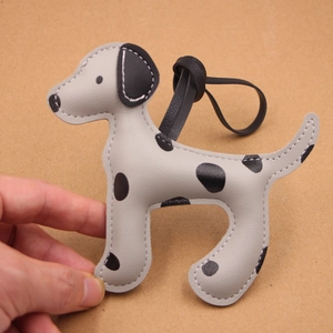 Détail de breloque dalmatien en cuir gris avec taches noires et coutures artisanales précises
