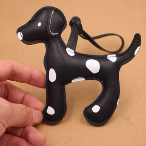 Détail d'un charme de sac en cuir motif chien tacheté noir et blanc avec cordon en cuir