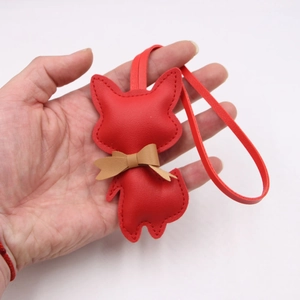 Close-up of a red leather fox charm featuring a brown bow tie and detailed stitching
