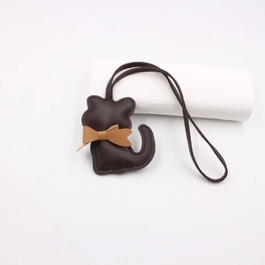Detail of dark brown leather cat bag charm with tan bow and contrast stitching