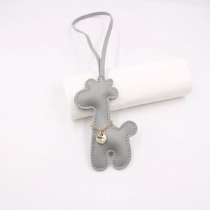 Close-up of gray leather giraffe bag charm with gold chain and detailed stitching