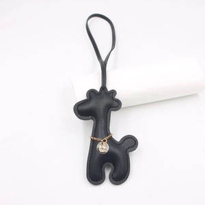 Detail of black leather giraffe charm with fine stitching and golden chain accessory