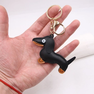 Detail of dachshund keychain featuring black leather texture and gold hardware