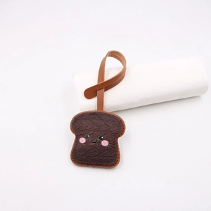 Close-up of a cute brown toast leather charm with cartoon expression and hanging strap