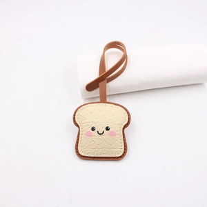 Cute toasted bread leather bag charm with smiling face and woven texture on white background