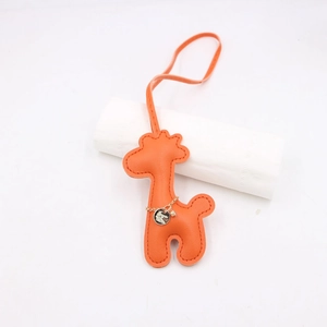 Close-up of an orange leather giraffe bag charm with fine stitching and gold chain detail