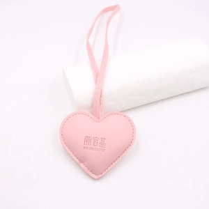 Pink heart-shaped leather bag charm with decorative stitching and long strap