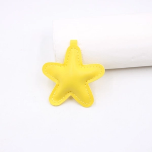 Detail of yellow star-shaped PU leather keychain with white contrast stitching