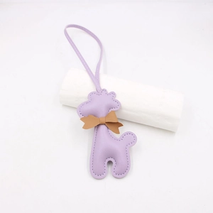 Détail macro du charm girafe en cuir violet avec nœud marron et couture fine