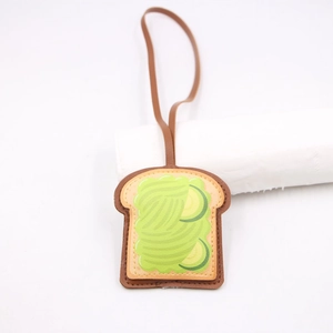 Dettaglio macro del ciondolo per borsa in pelle a forma di toast con motivo avocado