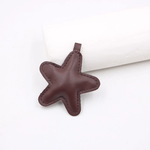 Detail of a dark brown star-shaped leather pendant with visible stitching and a top loop