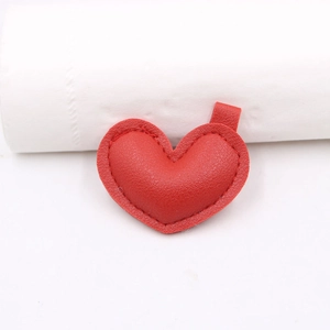 Vista macro dell'accessorio a cuore in pelle rossa con trama litchi e cuciture fini