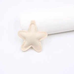 Detail of a beige star-shaped leather pendant with fine stitching and soft texture for DIY