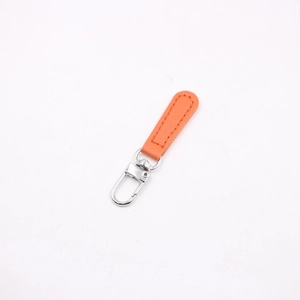 Close-up of orange leather charm with silver alloy lobster clasp and refined stitching