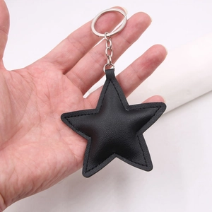 Close-up of a black star-shaped leather keychain with white stitching and silver metal ring