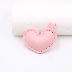 Dettaglio di un ciondolo a cuore in ecopelle rosa con cuciture rifinite e passante