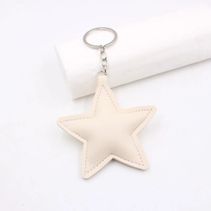Close-up of star-shaped cream leather keychain with stitching and silver metal ring