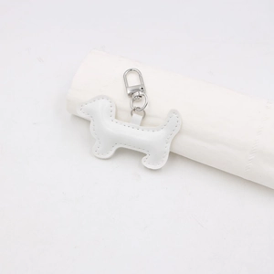 Détail d'un pendentif teckel en cuir PU blanc avec fermoir argenté et coutures fines