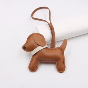 Close-up of handmade brown leather puppy bag charm with white collar and long lanyard