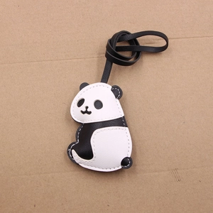 Cute panda shaped leather keychain with black and white stitching on brown background