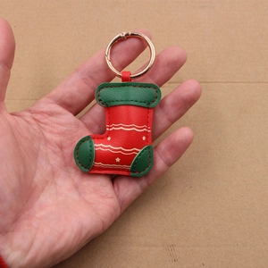 Close-up of red and green leather Christmas stocking keychain with gold star prints