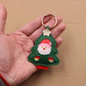 Close-up of a handmade leather Christmas tree keychain with Santa Claus and golden clasp